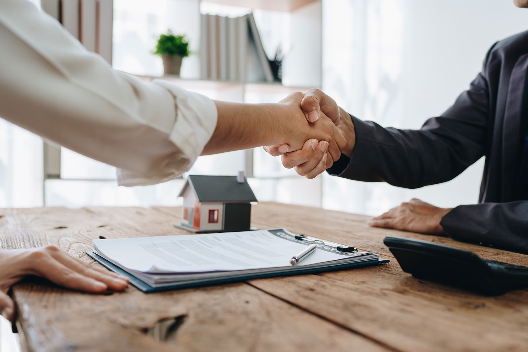 shaking hands over contract on a desk